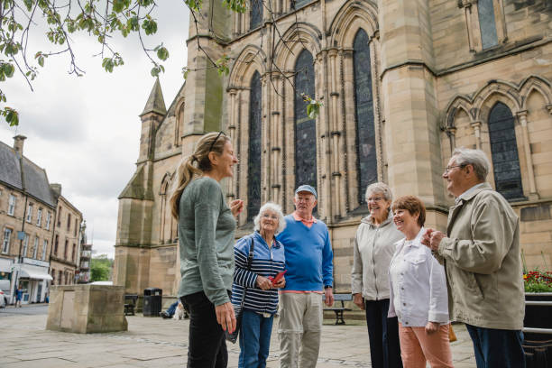 Senior group are doing a local tour in Northumberland with a guide. They are outside of Hexham Abbey Cathedral.